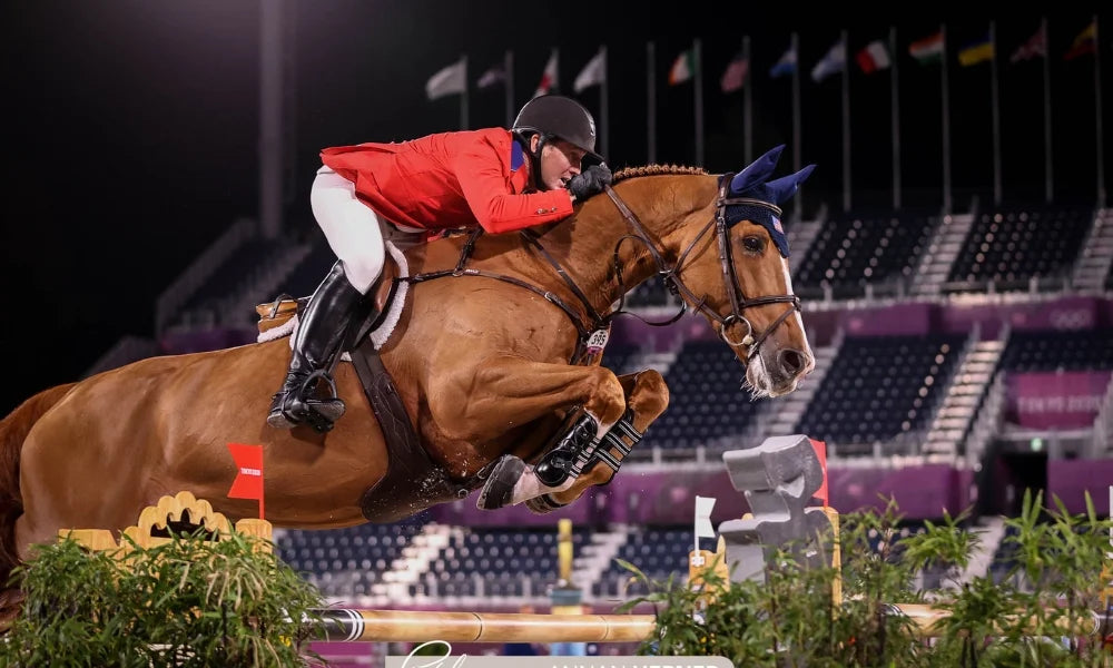 Equestrian on horseback jumping over a fence in an arena