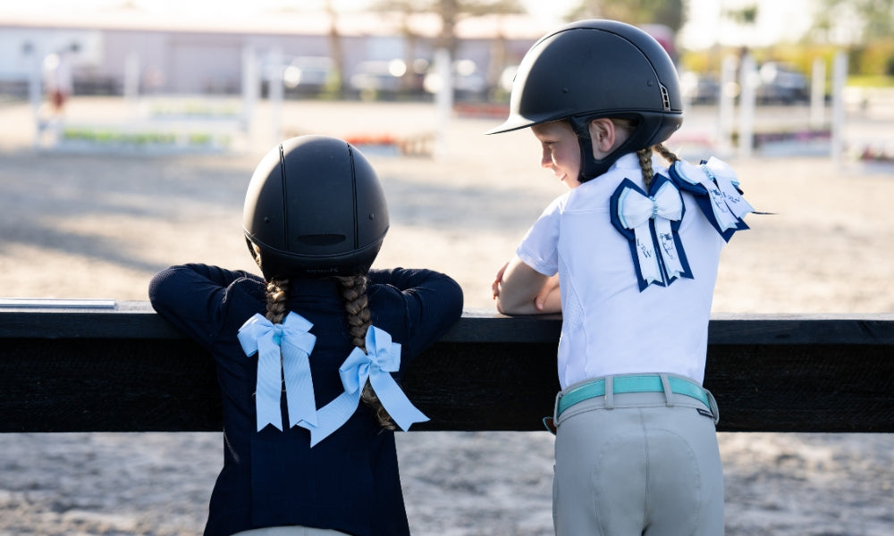 Two young riders in show bows looking into a show ring